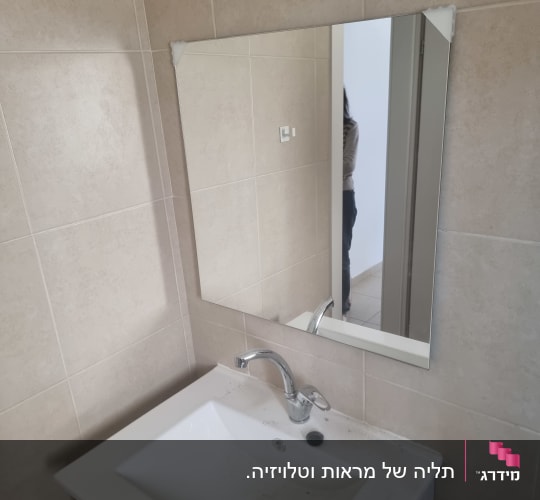 כיור עם ברז ומראה בחדר אמבטיה